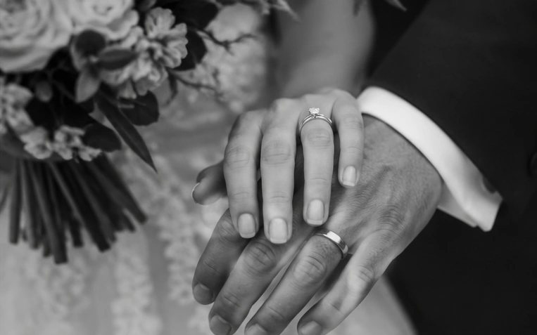 Mains des mariés avec leurs alliances, photo en noir et blanc